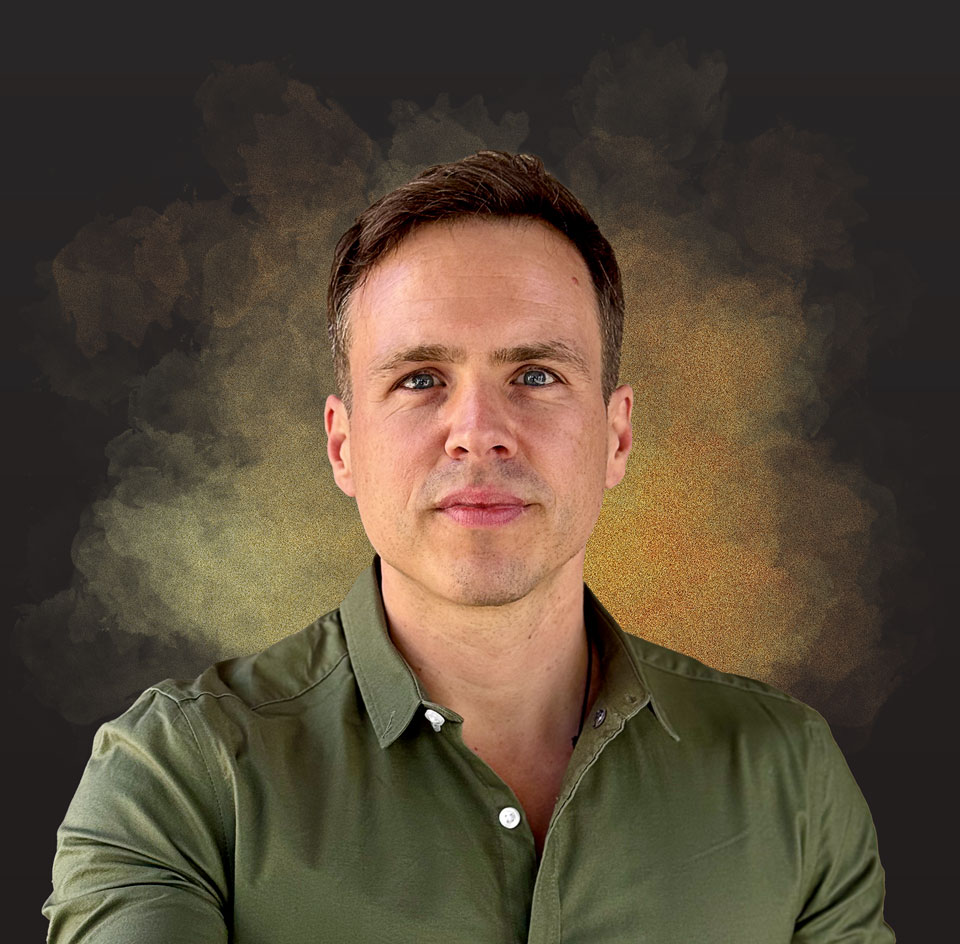 Jakob_black_neu_gerade_Staub Dieses Bild zeigt Jakob Fux in Nahaufname mit einer Hand vor dem linken Auge, deren Daumen und Zeige-Finger eine Runde "Linse" formen.